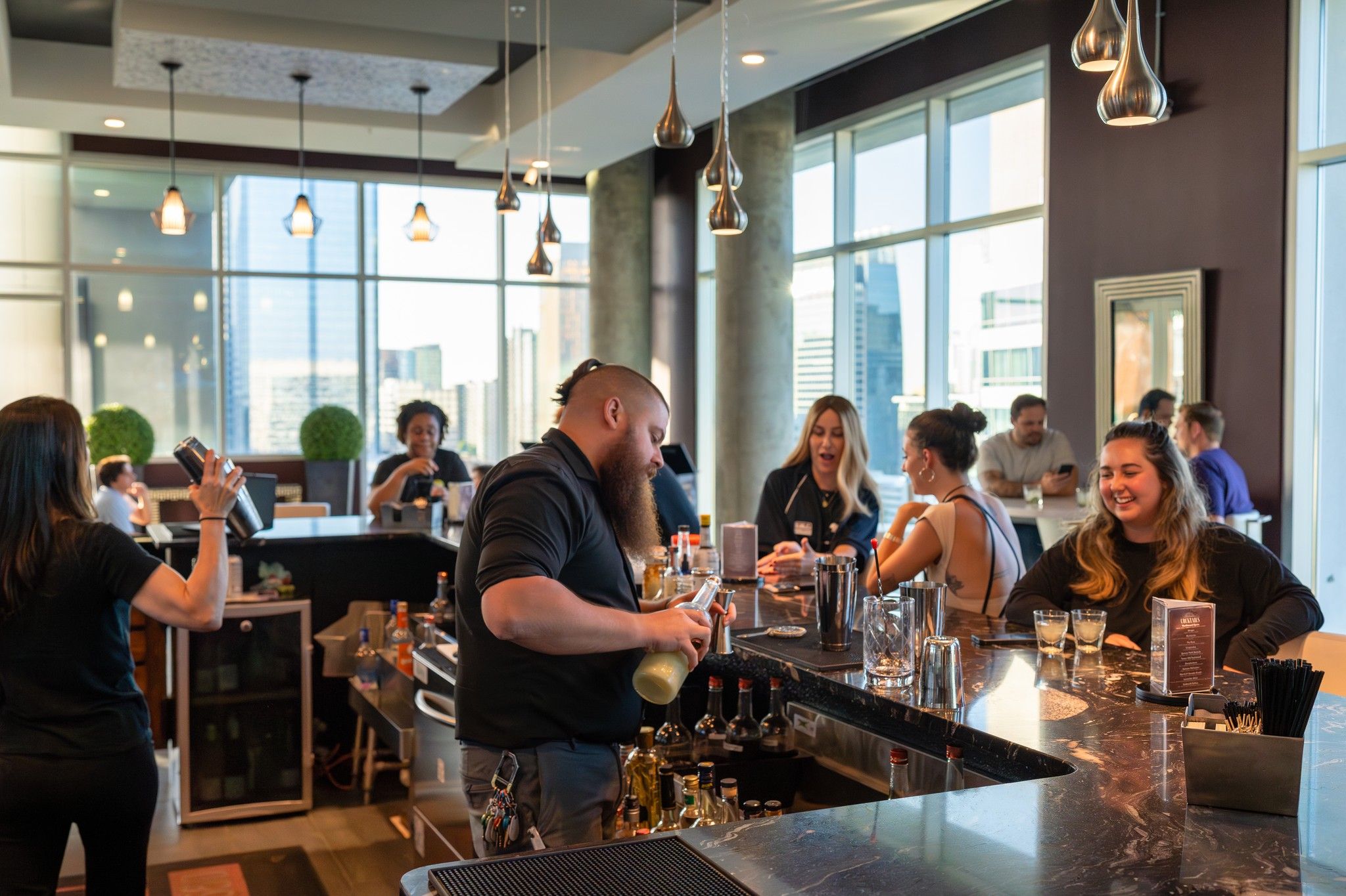 Residents chatting and being served cocktails at the rooftop bar at Uptown 550 on Brooklyn apartments