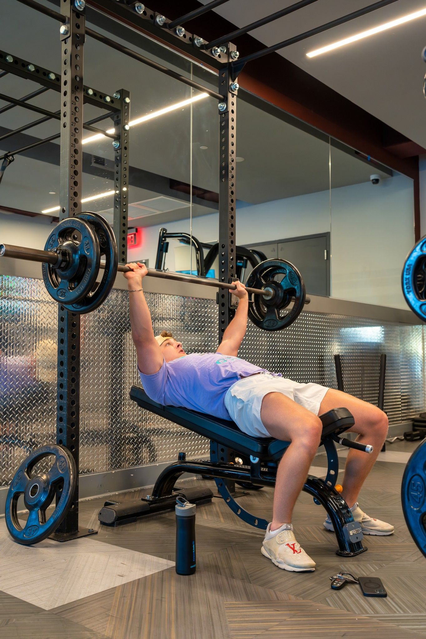 A resident doing bench presses with the weights in the fitness center at Uptown 550 on Brooklyn apartments