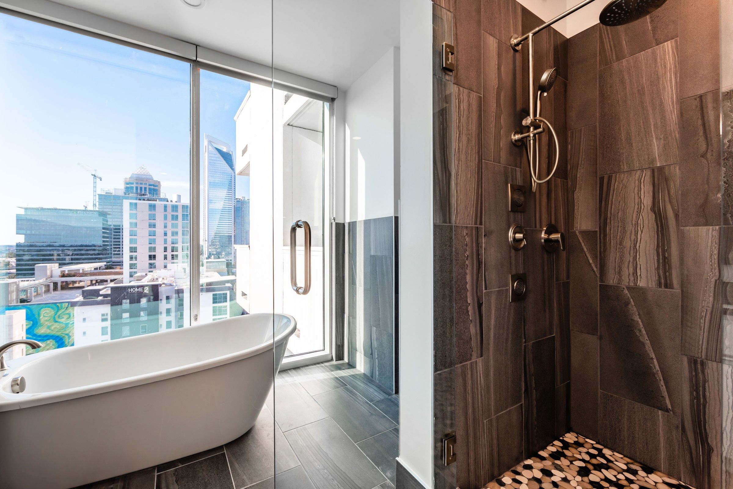 Uptown 550 luxury bathroom with floor to ceiling windows, soaking tub, and modern rain shower