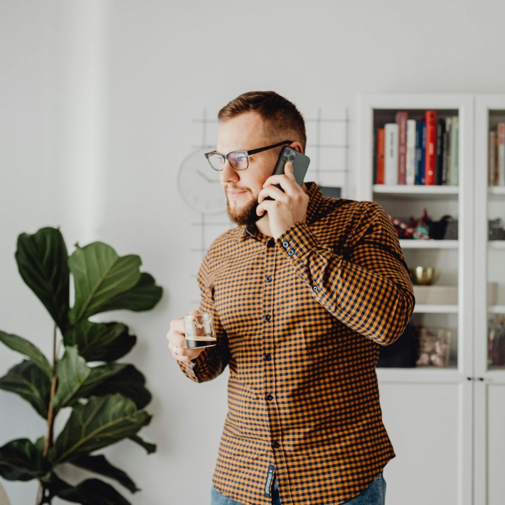 Young intellectual man with a cold brew on his cell phone